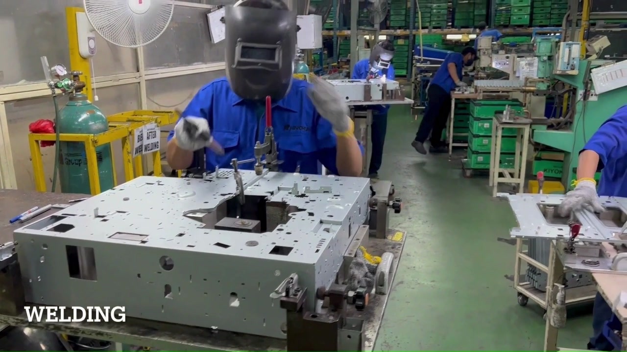 An operator wearing a welding helmet working on tooling